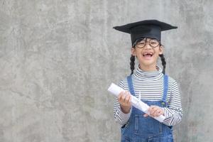 contento asiatico scuola ragazzo diplomato nel la laurea berretto foto