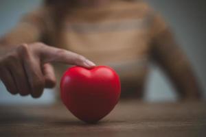 femmina mani Tenere rosso cuore, mondo mentale Salute giorno e mondo cuore giorno, vita e Salute assicurazione, csr sociale responsabilità, foto