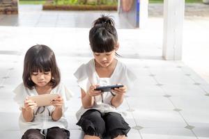 fratello ragazze Guardando loro smartphone su bianca sfondo. sociale concetto di nuovo tecnologia persone dipendenza foto