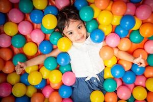 contento asiatico ragazza giocando nel colorato palle piscina foto