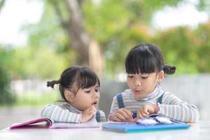 Due alunno poco asiatico ragazze lettura il libro su tavolo foto