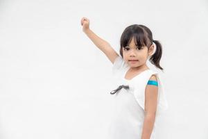 asiatico poco ragazza mostrando il suo braccio dopo avuto vaccinati o inoculazione, bambino immunizzazione, covid delta vaccino concetto foto