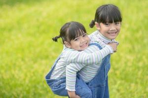 asiatico poco ragazza con Sambuco sorella a un' parco equitazione su sua indietro foto