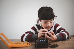 gli studenti asiatici imparano a casa a codificare auto robot e cavi di schede elettroniche in stelo, vapore, matematica ingegneria scienza tecnologia codice informatico in robotica per bambini concetto. foto