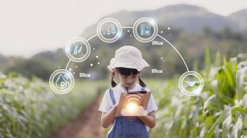 il poco ragazza usi un' tavoletta per analizzare il crescita di impianti nel il agricolo tracciare e visivo icona., il agricolo tecnologia concetto. inteligente agricoltura apprendimento concetto foto