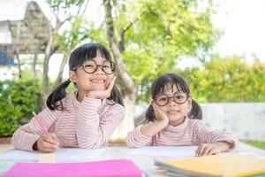 Due asiatico bambini fare compiti a casa insieme a casa foto