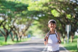 contento bambino ragazza in esecuzione nel il parco nel estate nel natura. caldo luce del sole bagliore. asiatico poco è in esecuzione nel un' parco. all'aperto gli sport e fitness, esercizio e concorrenza apprendimento per ragazzo sviluppo. foto