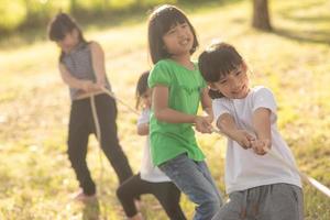 bambini giocando tirare di guerra a il parco su tramonto foto