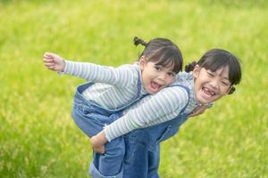 asiatico poco ragazza con Sambuco sorella a un' parco equitazione su sua indietro foto