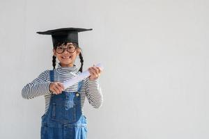 contento asiatico scuola ragazzo diplomato nel la laurea berretto foto