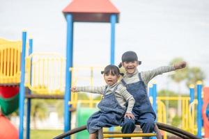 carino poco ragazze fratelli avendo divertimento su terreno di gioco all'aperto su un' soleggiato estate giorno. attivo sport tempo libero per bambini foto