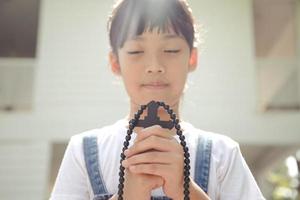 poco asiatico ragazza preghiere con Tenere il attraverso, cristiano concetto.