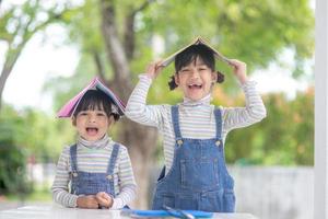 carino asiatico bambini lettura un' libro su il tavolo foto