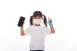 asiatico ragazza indossare maschera pulizia smartphone schermo con alcol.on bianca sfondo. concetto di pulizia sporco schermo Telefono per malattia prevenzione a partire dal batteri. foto