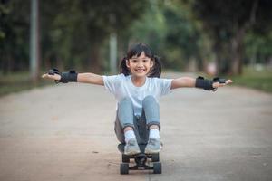 carino poco ragazza giocando skateboard o Surf pattinare nel il pattinare parco foto