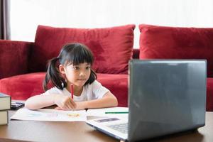 asiatico ragazza alunno in linea apprendimento classe studia in linea con il computer portatile a casa. foto