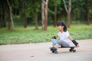 carino poco ragazza giocando skateboard o Surf pattinare nel il pattinare parco foto