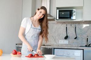 giovane donna prepara e tagli rosso Mela su taglio tavola. cucinando salutare cibo. foto