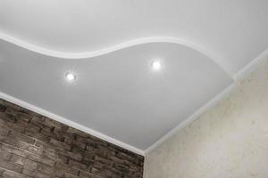 dettaglio di angolo soffitto con intricato corona modanatura. sospeso soffitto e cartongesso costruzione nel vuoto camera nel appartamento o Casa. allungare soffitto bianca e complesso forma. foto