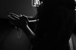 silhouette di una donna che tiene un rosario foto
