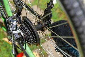 l'uomo meccanico della bici ripara la bicicletta nell'officina di riparazione della bicicletta, all'aperto. la mano del ciclista il ciclista esamina, ripara il moderno sistema di trasmissione del ciclo. manutenzione della bici, concetto di negozio di articoli sportivi. foto