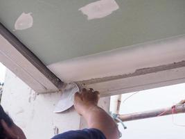 il soffitto lavoratore è intonacatura il soffitto articolazioni con alto qualità bianca gesso gesso per mantenere il articolazioni insieme. foto