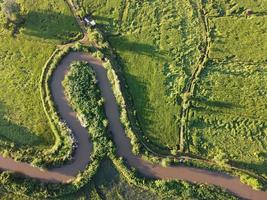 flussi meandro nel agricolo le zone durante il piovoso stagione con abbondanza di acqua. verde e caldo nel il mattina luce del sole. foto