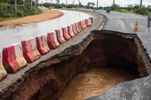 il strada era distrutto di acqua erosione causato di pesante pioggia e allagamento il strada. foto