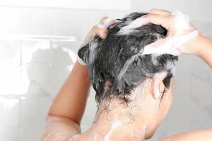 asiatico donna lavaggio sua capelli mentre assunzione un' doccia. foto