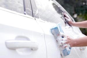 Questo uomo è lavaggio il auto e pulizia il macchina. foto