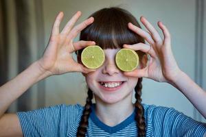 poco ragazza Tenere metà un' Limone nel sua occhi. salutare felicità foto