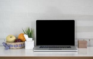 mockup di laptop accanto alla frutta su un tavolo foto