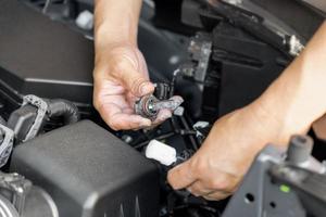 un' uomo hold xeno auto fari e confrontare con eccellente leggero guidato lampadina nel motore camera sostituzione il faro bulbi di il auto si servizio concetto foto