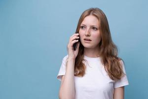 foto ritratto sorpreso ragazza parlando su Telefono su blu sfondo nel bianca