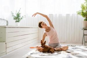 donna fare yoga con sua cane, godere e rilassare con yoga a casa, rilassare foto