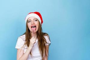 giovane donna nel bianca maglietta con Natale cappello su blu sfondo. carino Santa foto