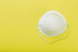 un' maschera per proteggere il tuo respiro a partire dal aria inquinamento o un scoppio di influenza o virus su un' giallo sfondo. foto
