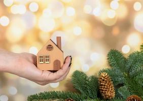 un' modello di un eco-friendly di legno Casa nel il mani su un' inverno sfondo. foto