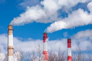 avvicinamento di il tubi di un' termico energia pianta con bianca vapore nel inverno. il concetto di ambientale inquinamento e emissioni di dannoso sostanze in il atmosfera. foto