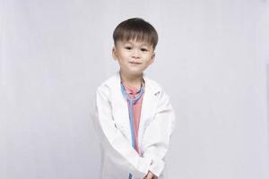 ragazzo indossare un' medico completo da uomo con un' medico stetoscopio su un' bianca sfondo. prescolastico bambini fare finta per essere un' pediatra. infanzia sognare di diventare un' medico foto