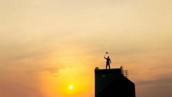 silhouette di uomo su rofftop al di sopra di cielo e sole leggero sfondo, affari, successo, comando, realizzazione e persone concetto foto