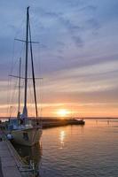 andare in barca nave nel il porto di lago vaetter a tramonto. faro nel il sfondo foto