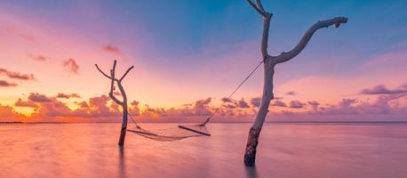 estate vacanza modello. tramonto al di sopra di acqua amaca nel tropicale mare laguna. rilassante romantico cielo con colorato nuvole, sognare vacanza, amore romanza coppia concetto. getto lontano, sorprendente natura paesaggio foto