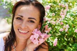 avvicinamento ritratto bellissimo donna nel parco con fioritura piccolo rosa Rose. foto