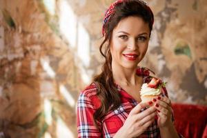 bellissimo donna con trucco è Tenere un' torta con fragole foto