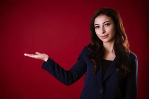 bellissimo attività commerciale donna su un' rosso sfondo detiene sua mano per il lato foto