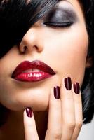 volto di donna con belle unghie scure e labbra rosse foto
