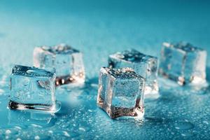 ghiaccio cubi siamo sparpagliato con acqua gocce sparpagliato su un' blu sfondo. foto