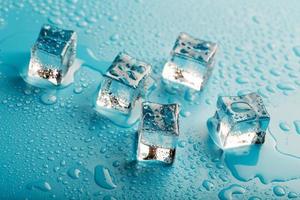 ghiaccio cubi con acqua gocce sparpagliato su un' blu sfondo, superiore Visualizza. foto