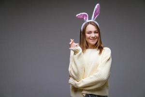 sorridente giovane ragazza con coniglietto orecchie Spettacoli un' mini cuore con dita foto